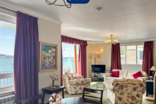 a living room with a couch and chairs and windows at bayviewapartment in Oban