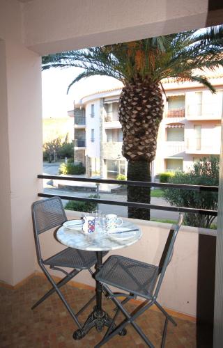 une table et des chaises sur un balcon avec un palmier dans l'établissement Com a Casa, à Collioure