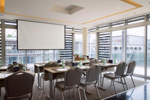 a conference room with tables and chairs and a large screen at The Abdali Boulevard Hotel in Amman
