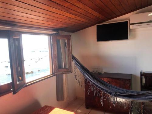 a hammock in a room with a window and a television at Pousada Tranquila in Morro de São Paulo