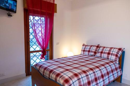 a bedroom with a bed with a plaid blanket and a window at UMA Home in Rome