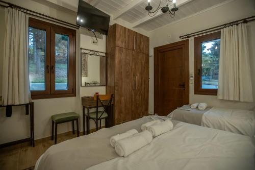 a bedroom with two beds with white sheets and windows at Ξαπόσταμα XAPOSTAMA - Ενοικιαζόμενα Δωμάτια in Kalyvia