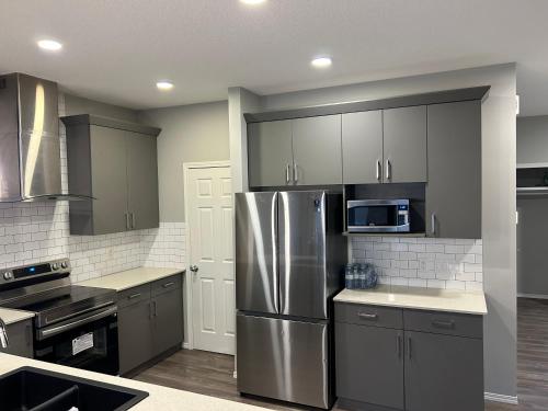 a kitchen with a stainless steel refrigerator and a microwave at Bedroom SW Edmonton HWY 2 near YEG in Edmonton