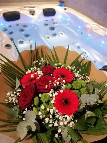 - un bouquet de fleurs rouges devant la baignoire dans l'établissement Autrement Spa, à Avelin