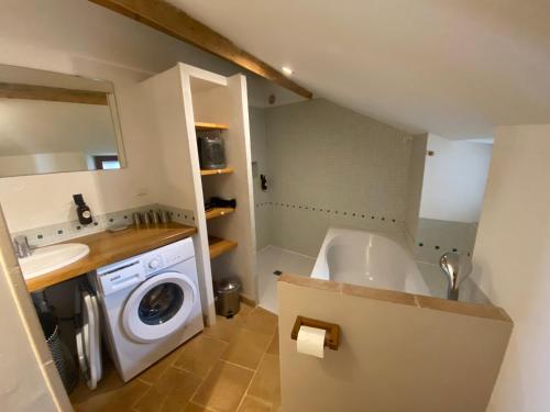 a bathroom with a tub and a washing machine at Les Caselles, Gîte et Chambre d'hôtes in Saint-Beauzély