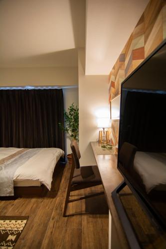 a hotel room with a bed and a flat screen tv at e-stay ebisu in Osaka