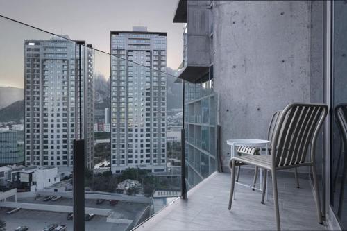 a chair on a balcony with a view of a city at Modern Apartments with Pool and Mountain views in Monterrey