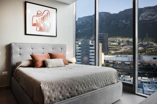 a bedroom with a bed and a large window at Modern Apartments with Pool and Mountain views in Monterrey