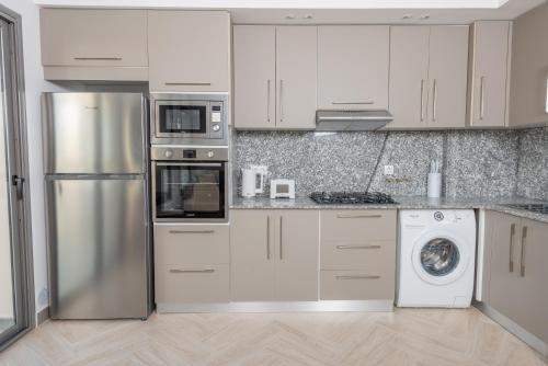 a kitchen with white cabinets and a stainless steel refrigerator at Immense appartement 6pièces au Golf in El Mouradia