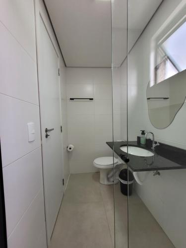 a white bathroom with a sink and a toilet at Perto da praia espaço amplo terraço, churrasqueira in Pontal do Paraná