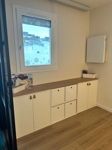 une cuisine avec des armoires blanches et une fenêtre dans l'établissement Appartement - Les Menuires, aux Menuires