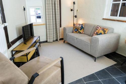 a living room with a couch and a television at Vakantiewoningen 'Hoeve de Witte Olifant' in Noorbeek