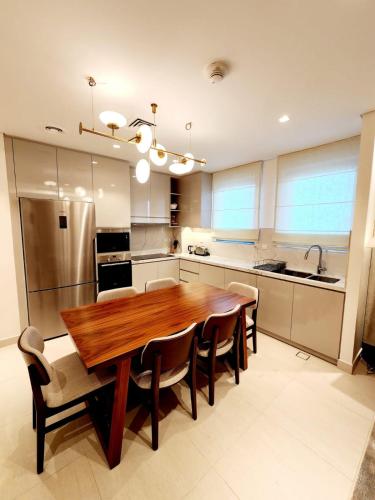 a large kitchen with a wooden table and chairs at Solo RealtyHH Apartments - Address Residence Fujairah in Sharm