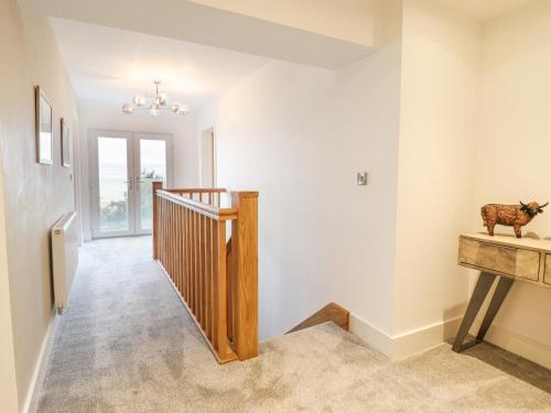 a hallway with white walls and a staircase with a cow statue at Aelfor in Harlech