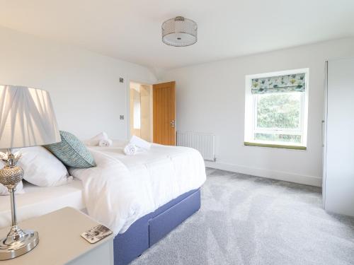 a white bedroom with a large bed and a table at Aelfor in Harlech