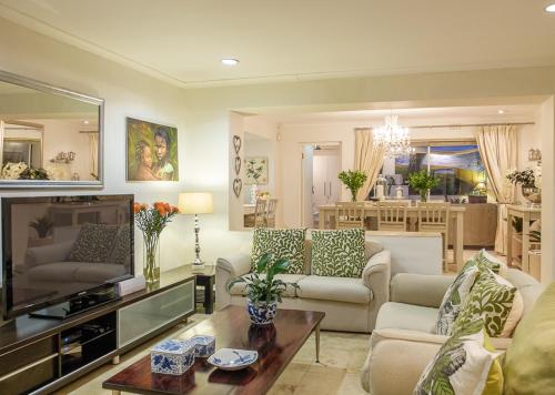 a living room with a couch and a tv at TarongaVilla in Constantia