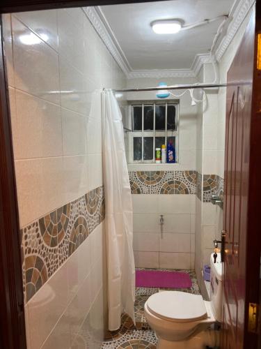 a bathroom with a toilet and a shower at Modern Haven in Nairobi