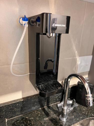 uma máquina de café sentada num balcão ao lado de um lavatório em Studio moderno e charmoso no melhor lugar da Barra em Salvador