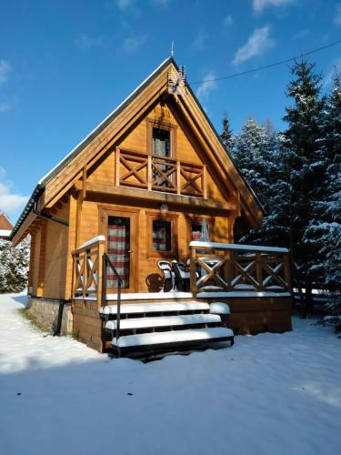 a log cabin in the snow with a porch at DOMKI JANOSIK - Janosik 2 Komfort in Łopuszna