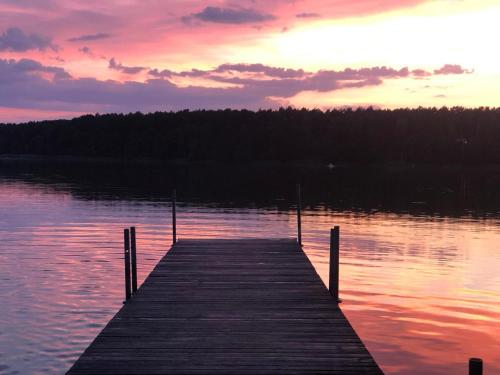 a dock on a body of water with a sunset at Las Biala's - Domki z sauną i jacuzzi w Puszczy Noteckiej - Tylko dla dorosłych in Biala