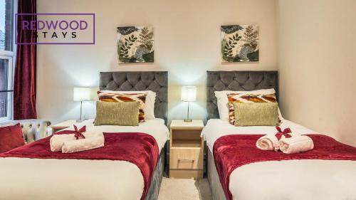 a bedroom with two beds with redwood stays sign on the wall at Newly Refurbished Everest Lodge Serviced Apartments for Contractors & Families, FREE WiFi & Netflix by REDWOOD STAYS in Farnborough