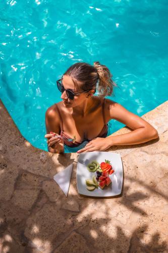 a woman in a bikini sitting in a pool with a plate of food at Encomendero Hotel -Centro Histórico- in Santa Fe de Antioquia