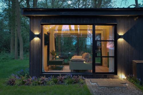 a small house with a large window in a yard at The Woods - Luxury cabin in a woodland setting in Hatfield Broad Oak