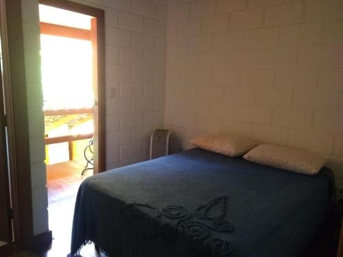a bedroom with a bed with a blue blanket at Chalé da Rô in Santo Antônio do Pinhal