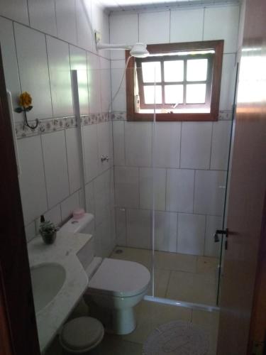 a bathroom with a toilet and a sink and a window at Chalé da Rô in Santo Antônio do Pinhal