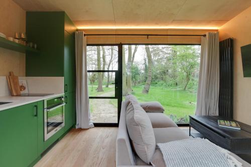 a living room with three couches and a large window at The Woods - Luxury cabin in a woodland setting in Hatfield Broad Oak