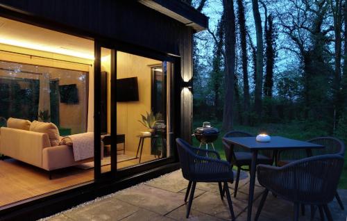 a patio with a couch and a table and chairs at The Woods - Luxury cabin in a woodland setting in Hatfield Broad Oak