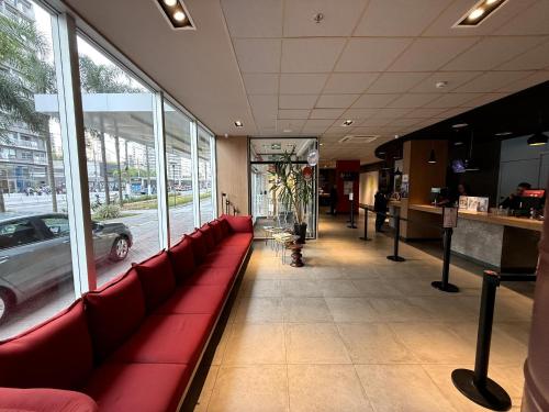 a restaurant with red couches in front of a window at ibis Sao Paulo Ibirapuera in Sao Paulo