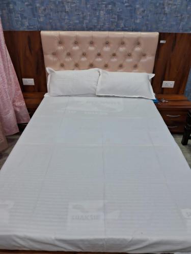 a large bed with white sheets and pillows at Maa kamakhya home stay in Varanasi