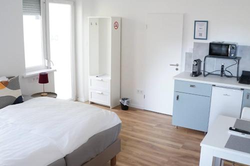 a white bedroom with a bed and a microwave at Pécs Centrum Apartman in Pécs