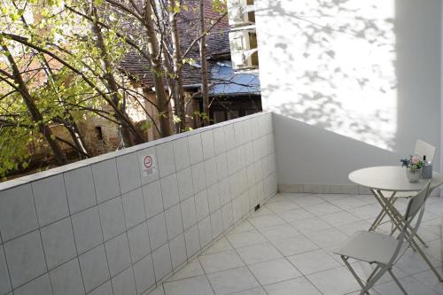 a white tiled wall with a table and two chairs at Pécs Centrum Apartman in Pécs