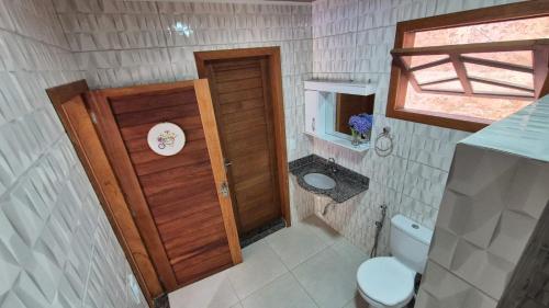 a small bathroom with a toilet and a wooden door at Casa Bourguignon in Vítor Hugo