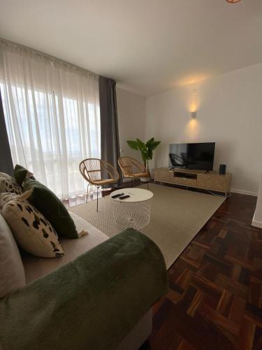 a living room with a couch and a flat screen tv at Cantinho dos M&M in Funchal