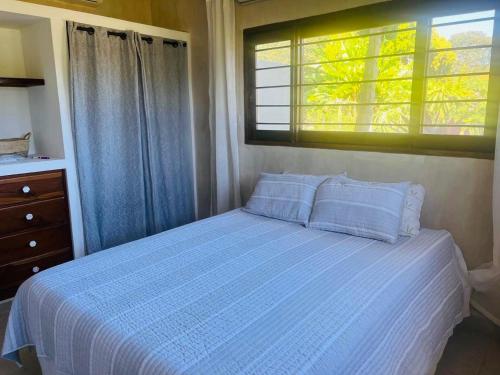 a bedroom with a bed with a blue comforter and a window at Pedasi, Casa Alegre in Pedasi Airport
