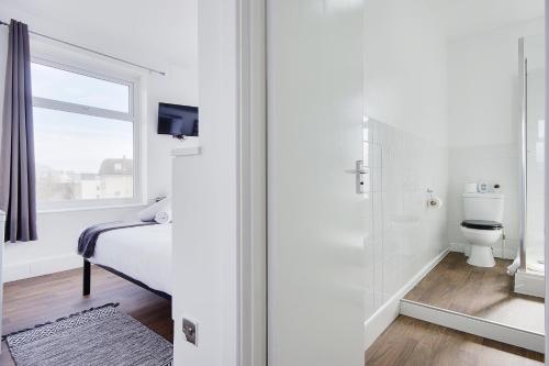 a white bathroom with a bed and a toilet at Azure Beach Hotel in Bournemouth