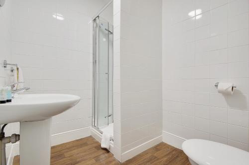 a white bathroom with a sink and a shower at Azure Beach Hotel in Bournemouth
