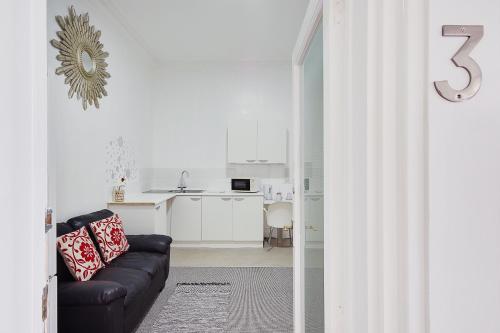 a living room with a black couch and a kitchen at Azure Beach Hotel in Bournemouth