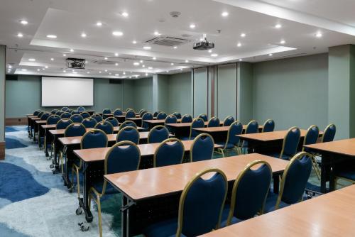 an empty classroom with tables and chairs and a screen at Hilton Porto Alegre, Brazil in Porto Alegre