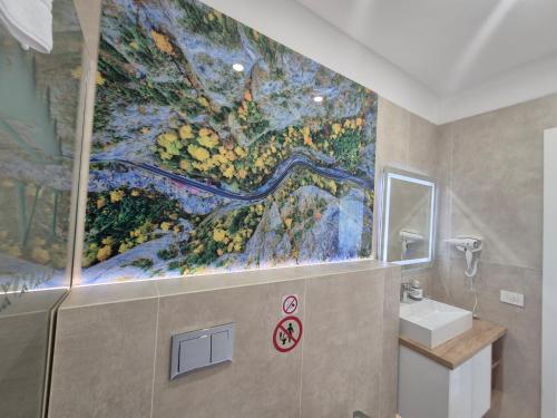a bathroom with a large painting on the wall at Holiday Village Tarcau in Tarcău-Gheuca