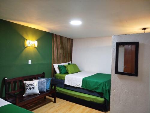 a bedroom with a bed with green walls and a mirror at HOSTAL LA BOQUILLA in Cartagena de Indias
