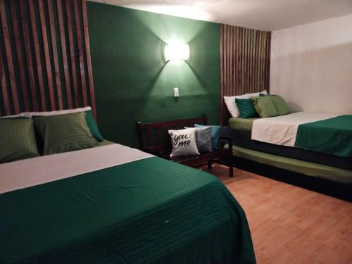 a bedroom with two beds and a green wall at HOSTAL LA BOQUILLA in Cartagena de Indias
