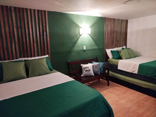 a bedroom with two beds and a green wall at HOSTAL LA BOQUILLA in Cartagena de Indias