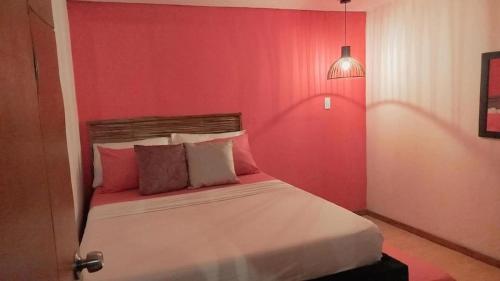 a bedroom with a red wall and a bed with pillows at HOSTAL LA BOQUILLA in Cartagena de Indias