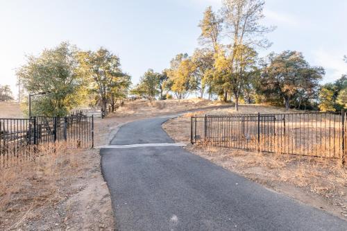 a winding road in a field next to a fence at Rolling Oaks Ranch - 200 Acres of Lakeside Beauty & Countryside Serenity in Mariposa