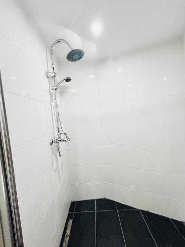 une douche dans une pièce blanche avec un sol en carrelage noir dans l'établissement Studio Royal Séjour proche centre, parking gratuit, à Saint-Quentin