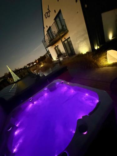 a purple hot tub in a backyard at night at Loox Ostrovo- Boutique House-noclegi nad morzem in Ostrowo
